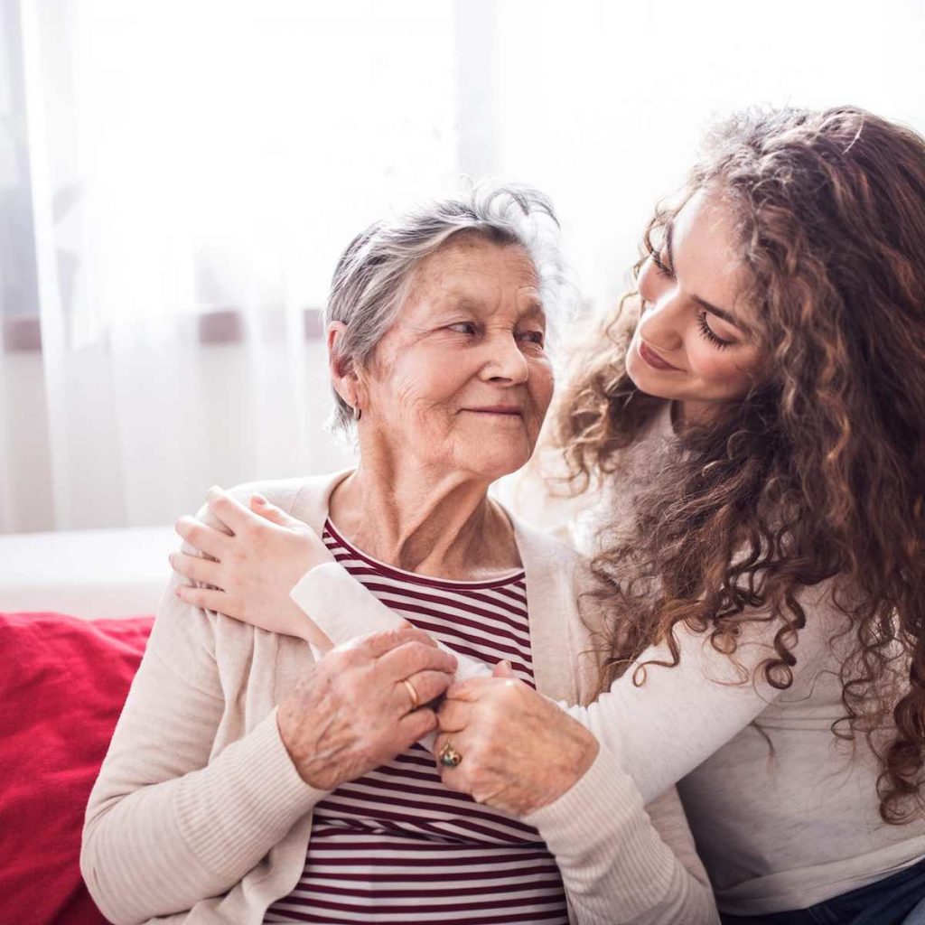 Mujer joven y cariñosa feliz y sonrisa abrazando una anciana